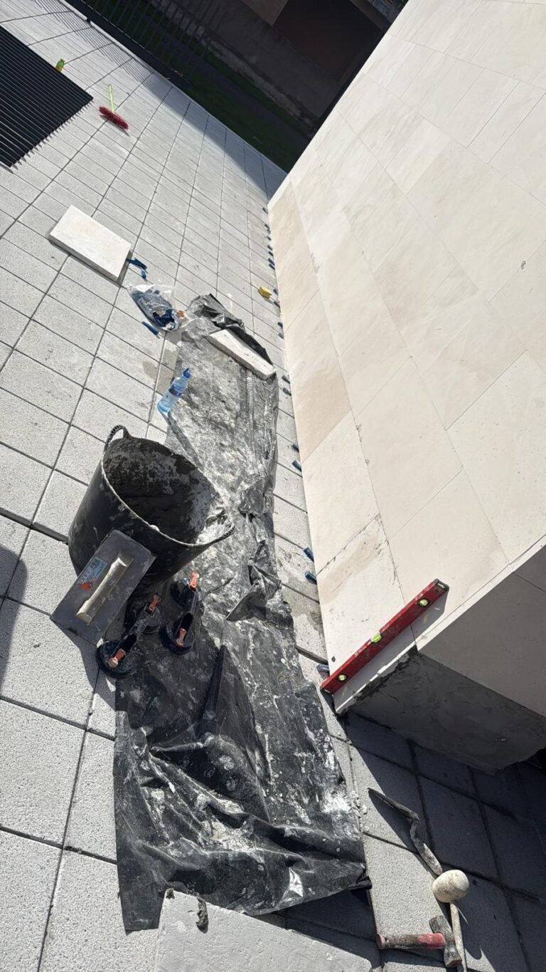 Colocación del mármol de la base de la fachada a doble encolado, con la llana dentada y el nivel