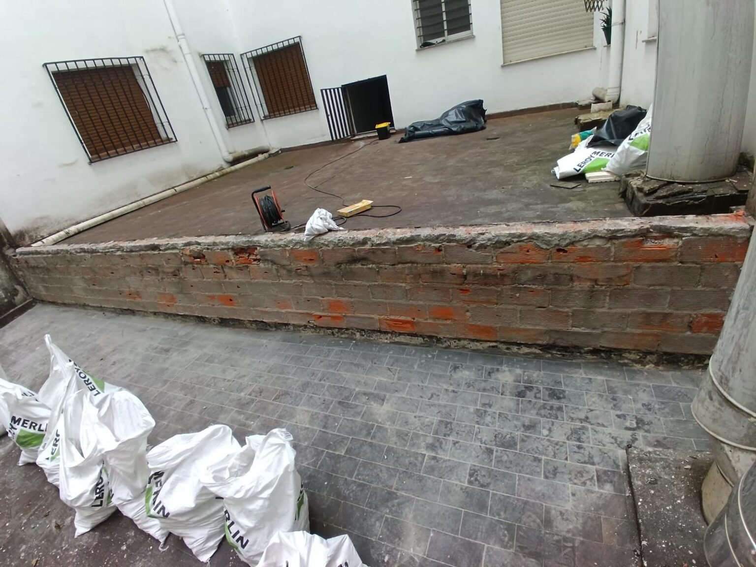 El muro exterior picado hasta el ladrillo, con el revestimiento antiguo retirado