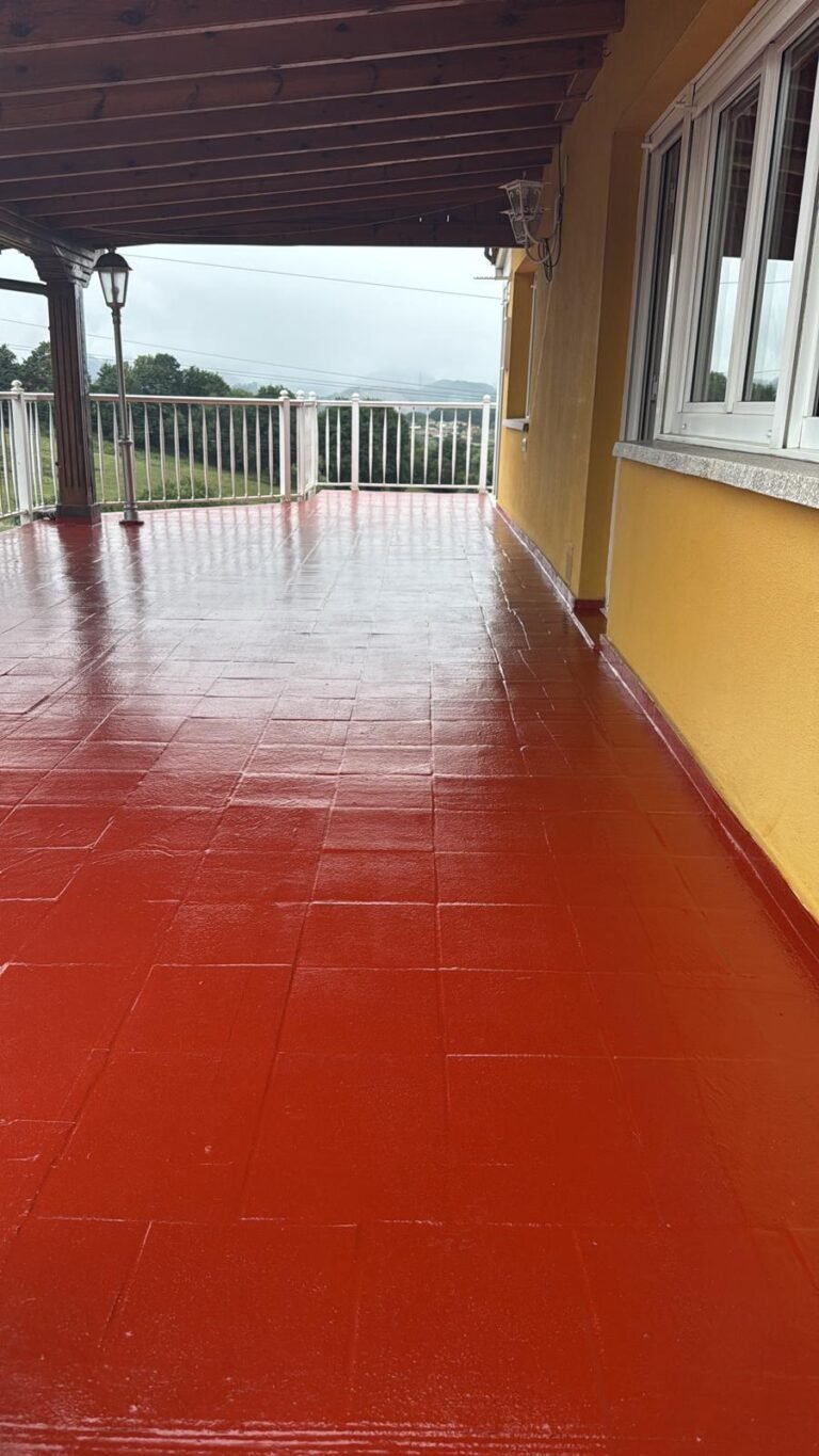 La terraza acabada en rojo, con la barandilla blanca y el valle al fondo