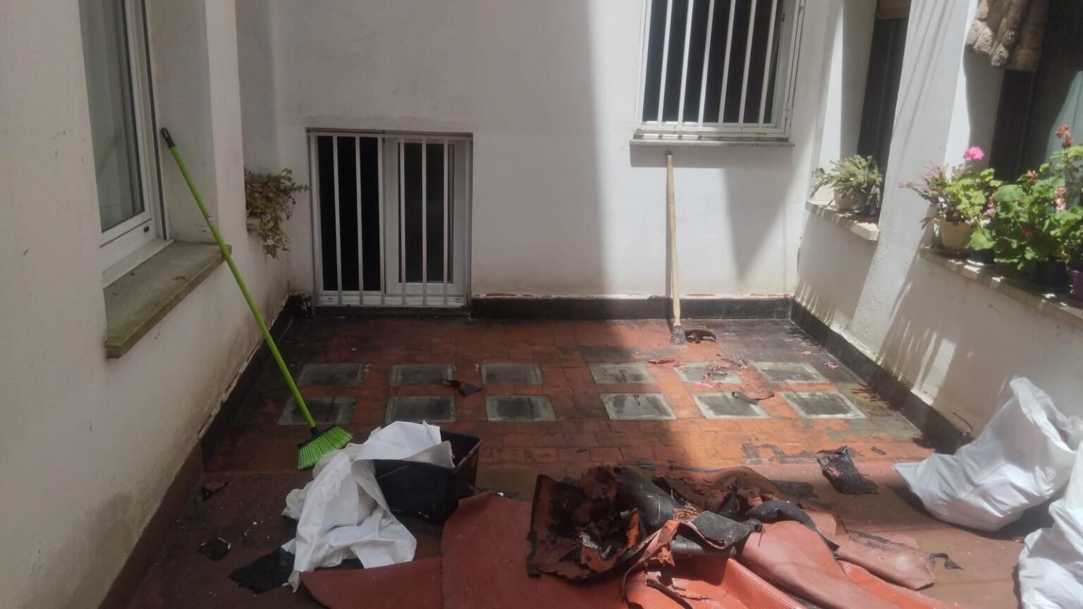 Patio antes de impermeabilizar, con el suelo de ladrillo sucio y las tapas de registro a la vista